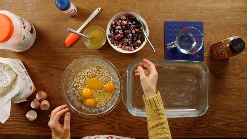 cracking eggs into soaked oats