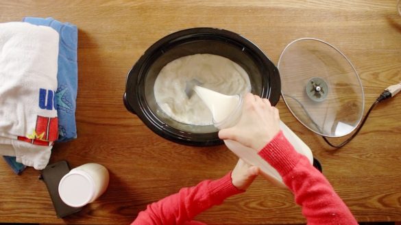 pouring fresh milk into crockpot for making yogurt