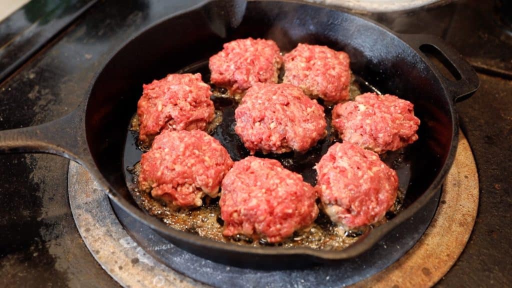 burgers sizzling on cast iron skillet
