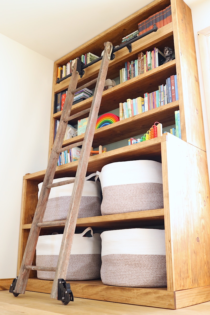 living room book and toy storage with library ladder