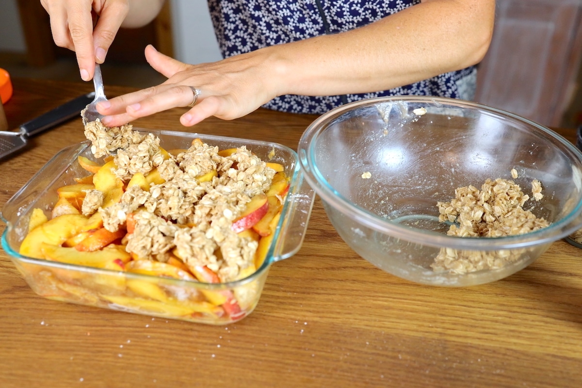 adding topping for peach crumble with oats