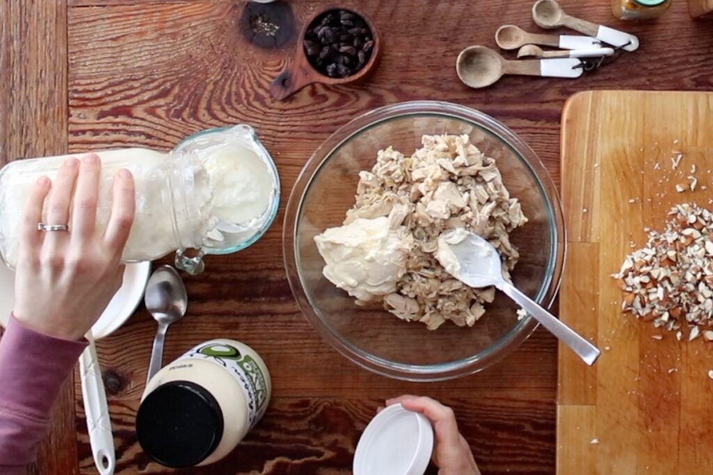 adding mayonnaise and yogurt to chicken salad