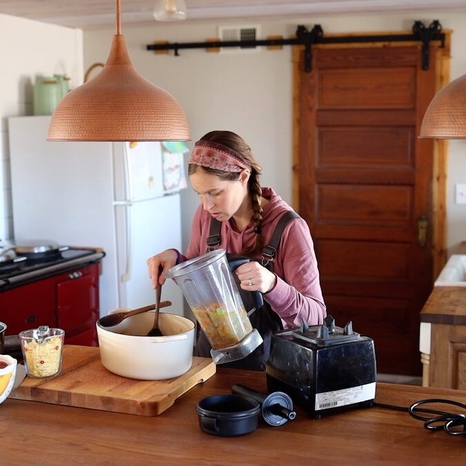 scooping soup into vitamix to blend