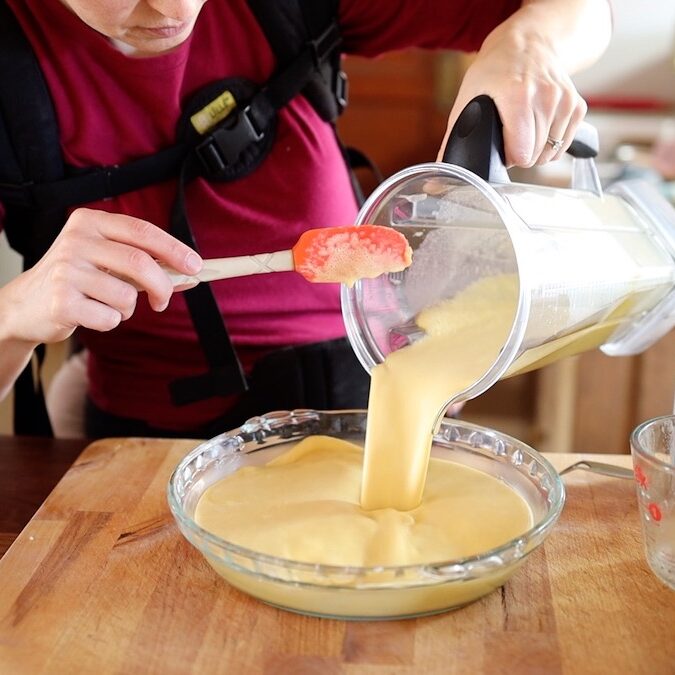 pouring blended custard pie batter into pie pan
