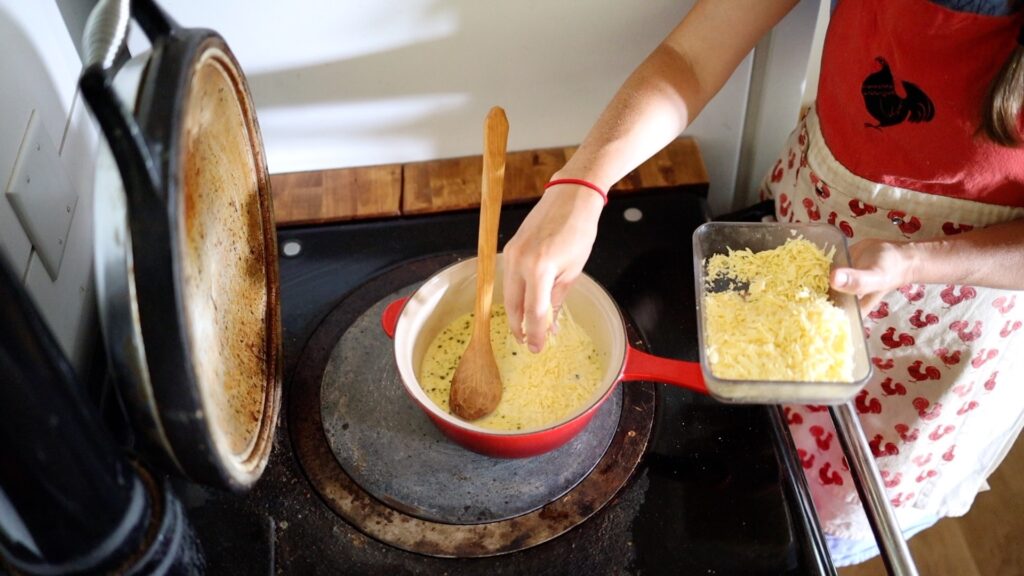 adding shredded cheese to sauce