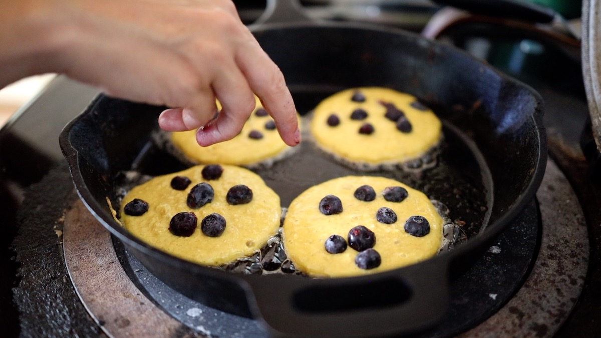 adding blueberries to pancakes