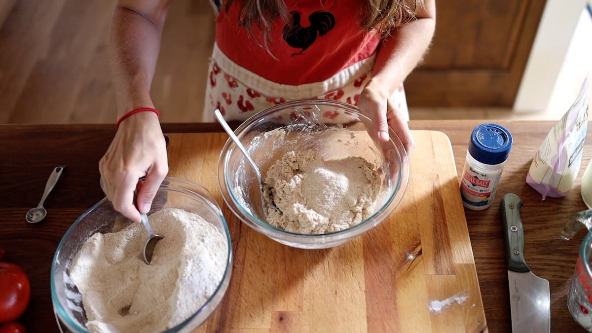 adding more flour while mixing pizza dough