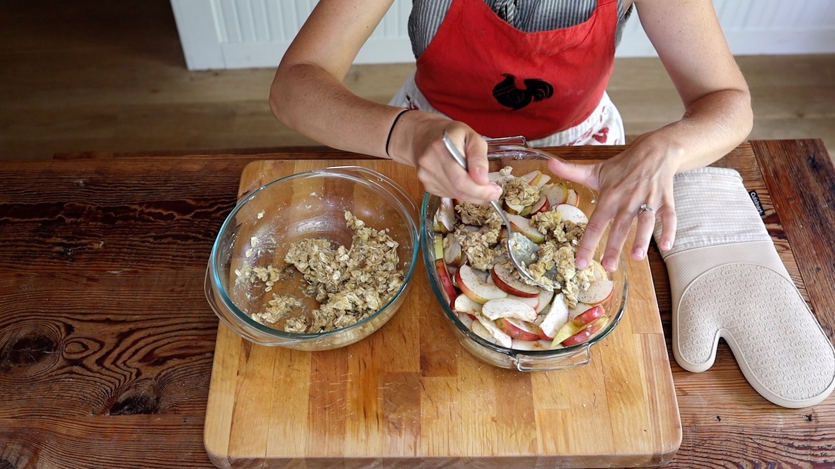 spooning crumble topping onto baked apples