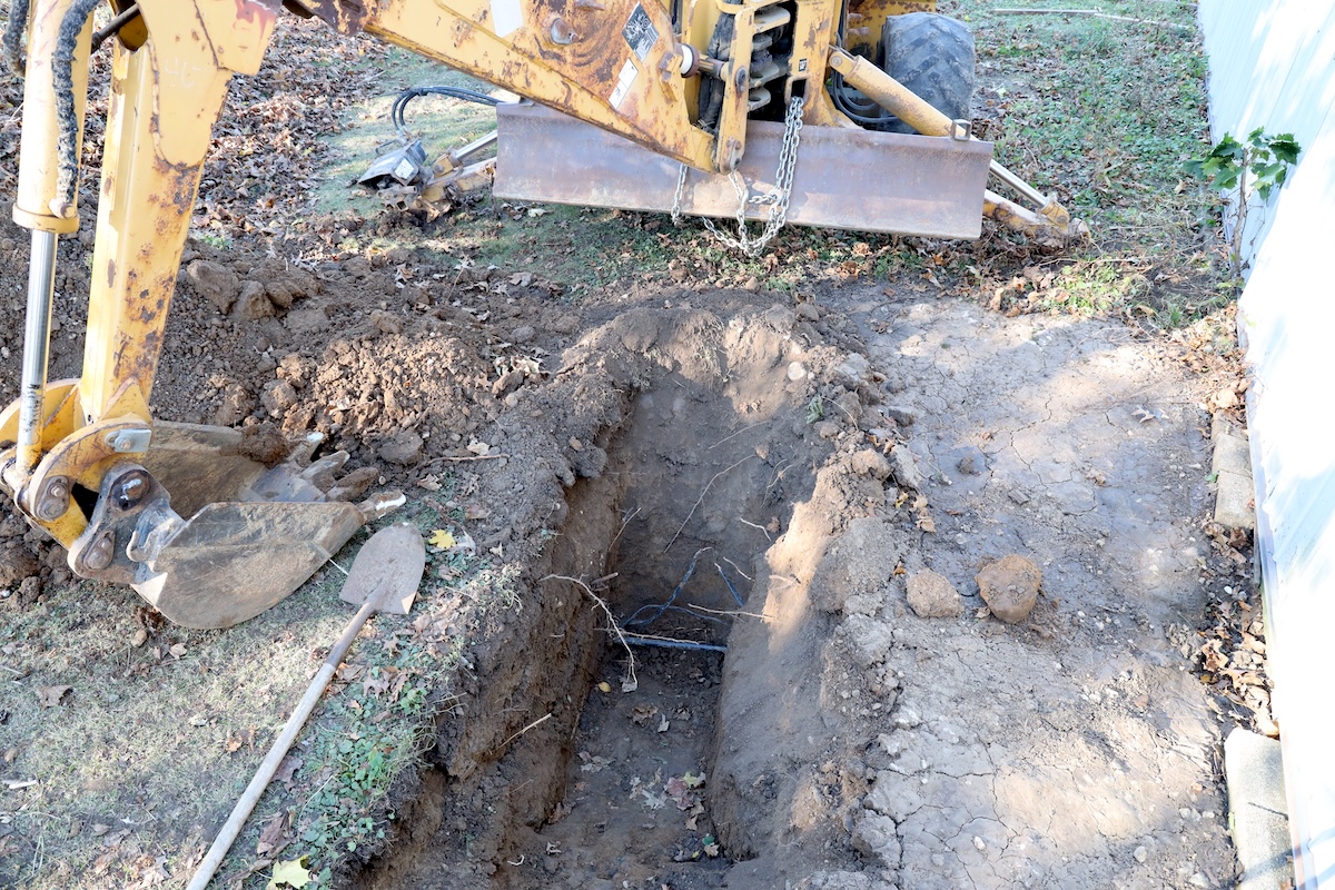 using excavator to dig up existing waterline