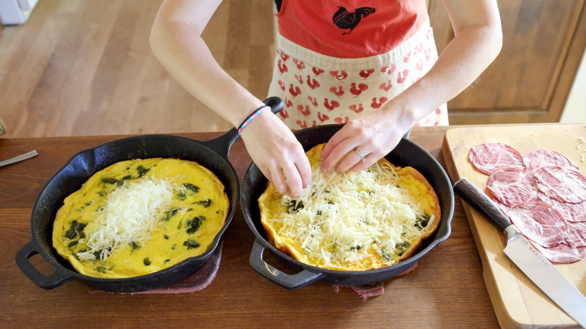 spreading shredded cheddar over savory dutch pancakes