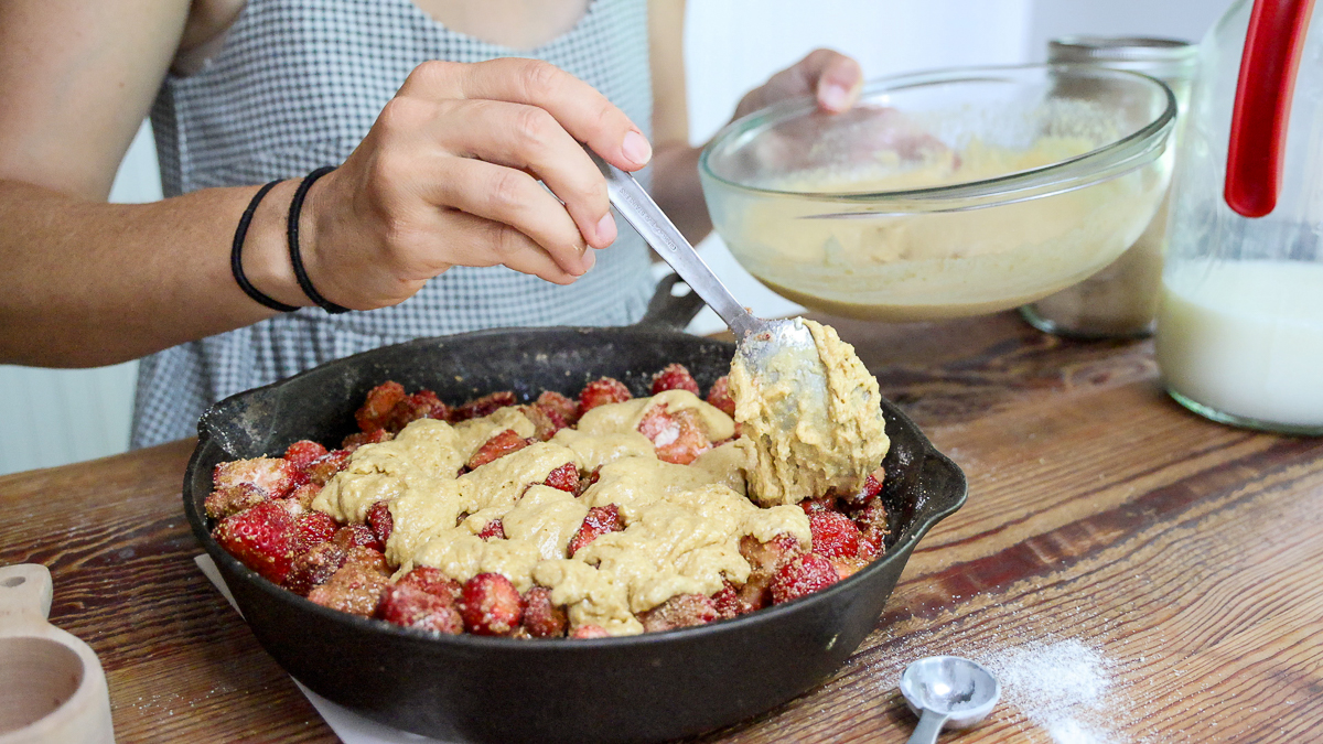 spooning batter over quick strawberry cobbler filling