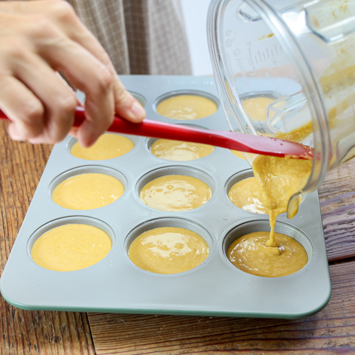 pouring oatmeal pumpkin muffin batter into muffin tin